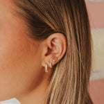 Close-up of an ear wearing gold earrings with a blurred background