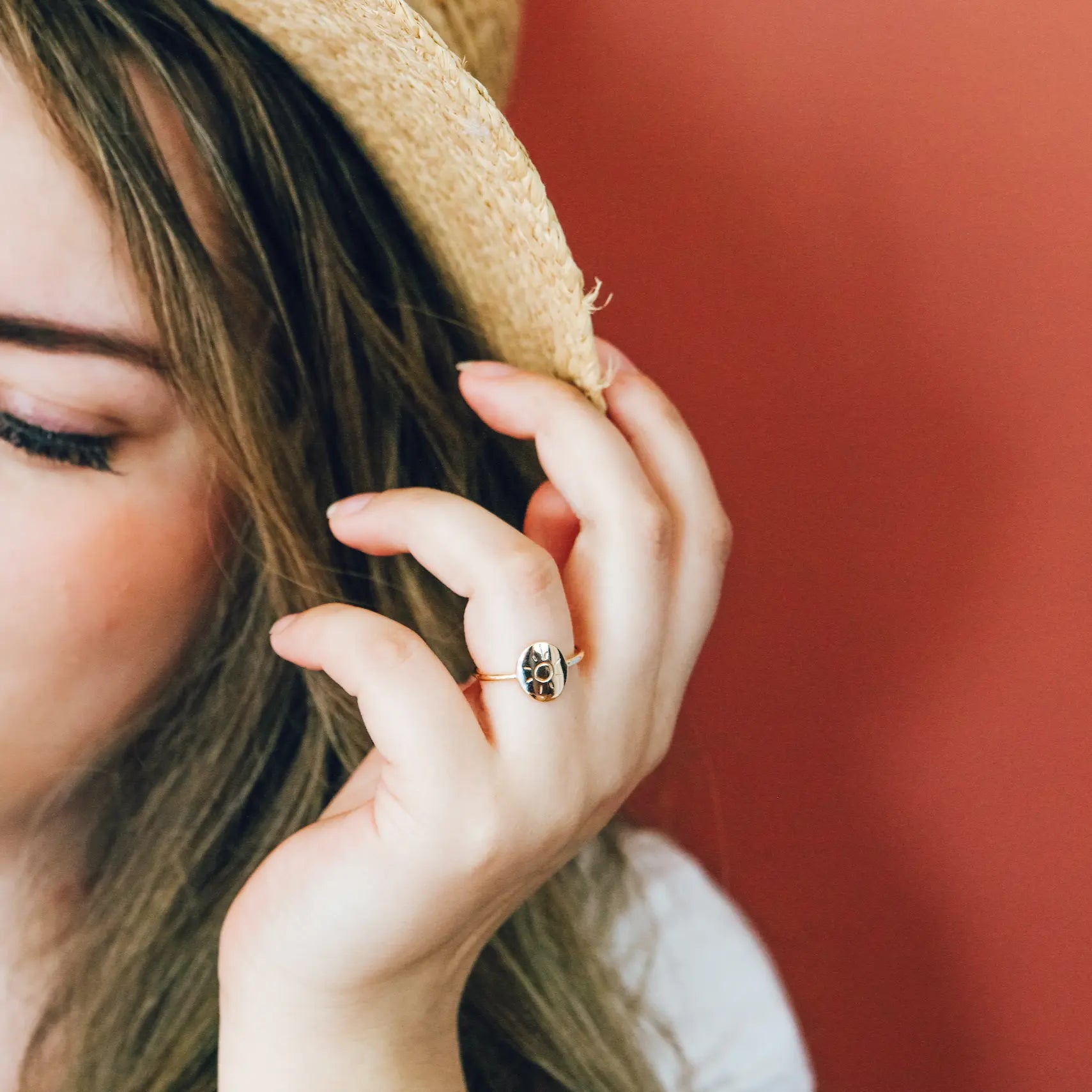 Close-up of a person wearing a straw hat and a ring with a paw print design.