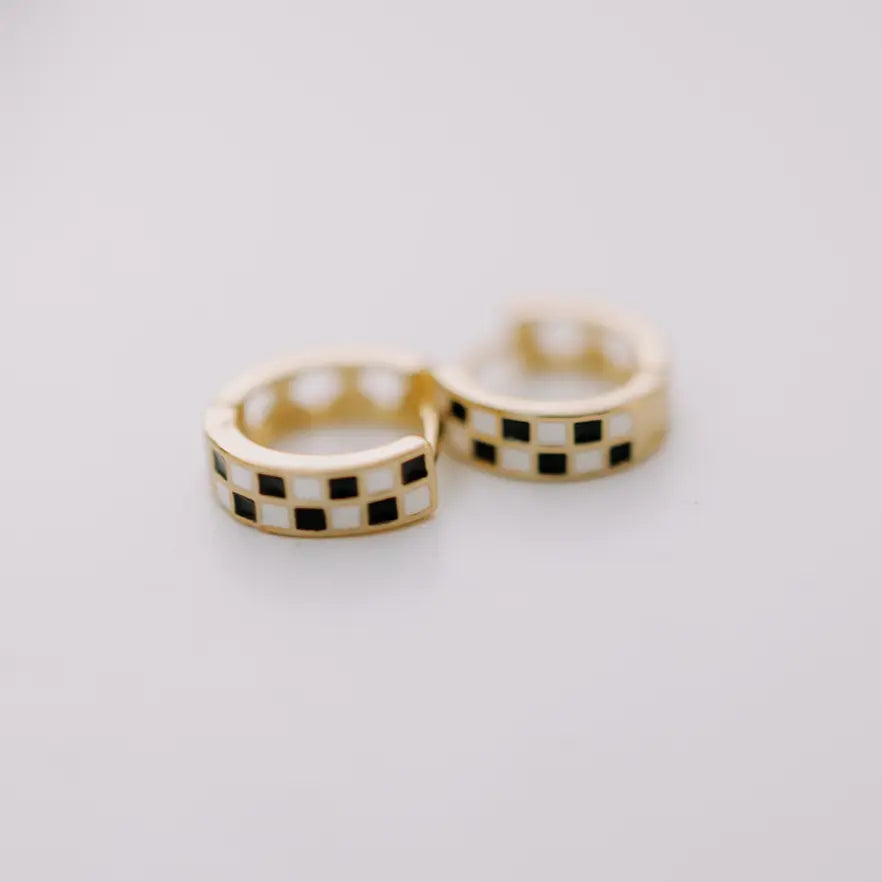 Pair of gold hoop earrings with black and white checkered pattern on a light gray background
