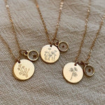 Three gold necklaces with floral pendants on a textured beige background