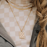 Checkered Necklace in Gold, a gold filled rectangle pendant necklace, layered with a herringbone chain and a beaded chain.